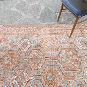 Puede incluir: Una alfombra vintage con un patr&oacute;n geom&eacute;trico en tonos rojos, azules y blancos. La alfombra tiene un aspecto descolorido y desgastado, lo que le da un aspecto r&uacute;stico y antiguo.