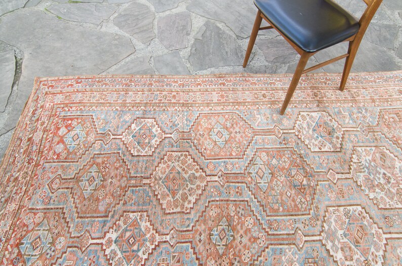 Puede incluir: Una alfombra vintage con un patr&oacute;n geom&eacute;trico en tonos rojos, azules y blancos. La alfombra tiene un aspecto descolorido y desgastado, lo que le da un aspecto r&uacute;stico y antiguo.