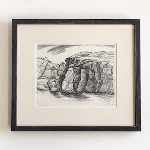 May include: Black and white drawing of a rocky cliff face with a body of water in the foreground. The drawing is framed in a black frame.