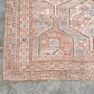 Puede incluir: Una alfombra vintage con un dise&ntilde;o persa tradicional. La alfombra tiene un fondo azul claro con un medall&oacute;n central en tonos de rosa, marr&oacute;n y blanco. La alfombra tiene un borde con flecos.