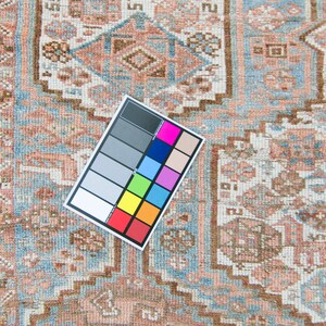 Puede incluir: Un primer plano de una alfombra de color azul claro y rosa con una tabla de colores de referencia. La alfombra tiene un dise&ntilde;o tradicional con detalles intrincados.