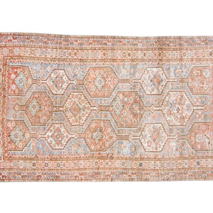 Puede incluir: Una alfombra vintage con un patr&oacute;n geom&eacute;trico en tonos rojos, azules y blancos. La alfombra tiene un medall&oacute;n central y un borde con detalles intrincados.