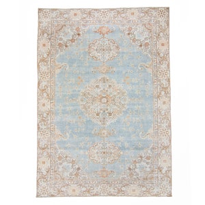Op de afbeelding: Een vintage tapijt met een lichtblauwe achtergrond en een beige en bruin bloemenpatroon. Het tapijt heeft een centraal medaillon en een rand met een herhalend bloemenpatroon.