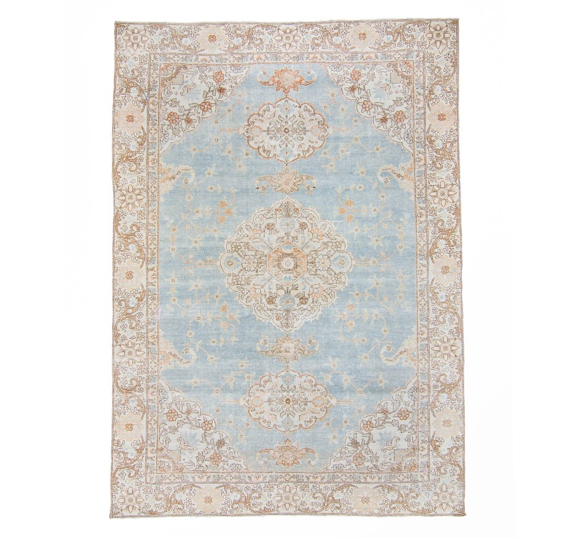 Op de afbeelding: Een vintage tapijt met een lichtblauwe achtergrond en een beige en bruin bloemenpatroon. Het tapijt heeft een centraal medaillon en een rand met een herhalend bloemenpatroon.