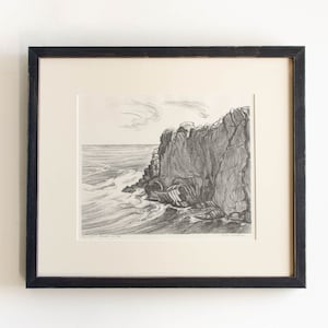 May include: Black and white print of a rocky cliffside with crashing waves. The print is framed in a black frame.