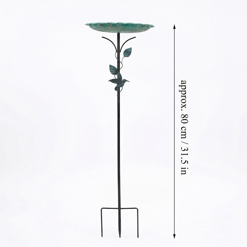 May include: A tall, black metal bird bath with a green, textured bowl. The bird bath is approximately 31.5 inches tall and features decorative leaves and a hummingbird. The base has a three-pronged stake for ground placement.