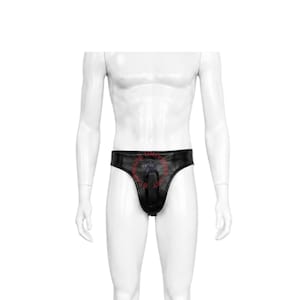 May include: A black jockstrap featuring a central vertical opening and a circular cutout. The waistband displays the red text STAR WARS UNIVERSE ART arranged in a circular pattern around the center. The garment is displayed on a white mannequin.