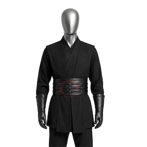 May include: A black long-sleeved tunic with a wrap-style front, paired with a wide black multi-layered belt featuring horizontal stitching and small metal studs. The outfit includes black forearm-length gloves and matching black trousers.