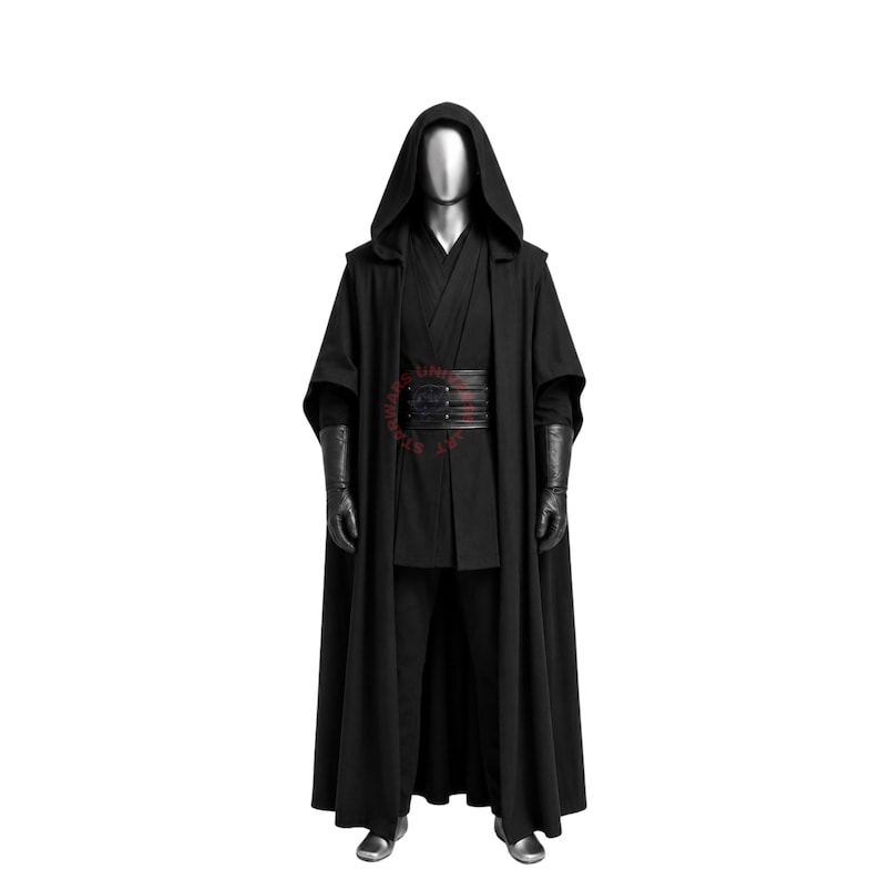 May include: A full-length black hooded cloak worn over a black tunic and trousers, featuring a wide, multi-layered black belt with horizontal stitching and long black gloves. The ensemble is displayed on a mannequin with a metallic silver head.