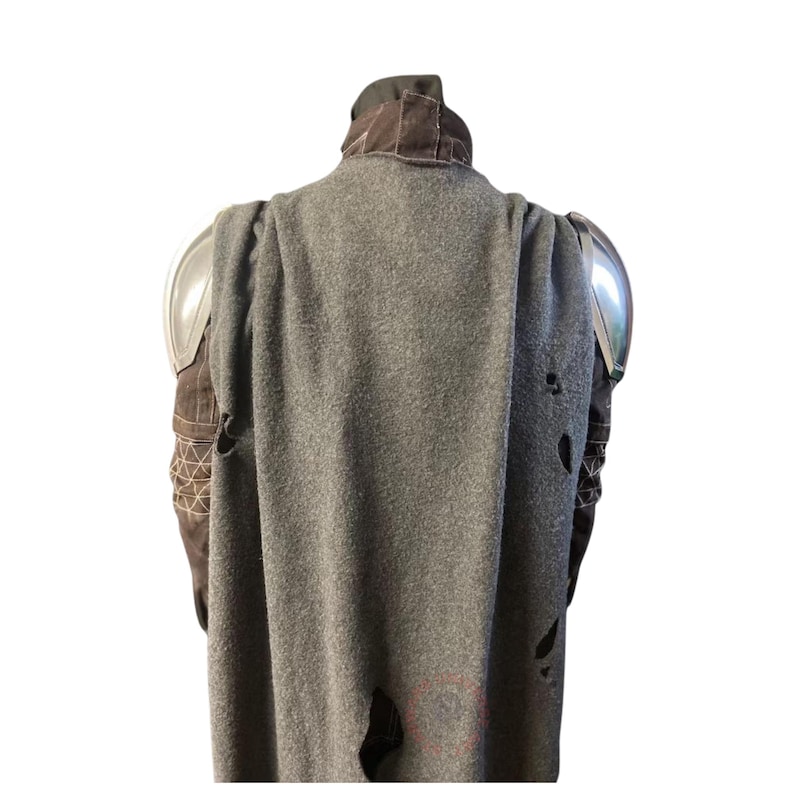 Op de afbeelding: Een grijze cape met versleten details, gecombineerd met bruine en zilveren bepantsering. De cape heeft een versleten uiterlijk met gaten en een textuur. De bepantsering omvat schouderstukken. De kraag is donkerbruin.