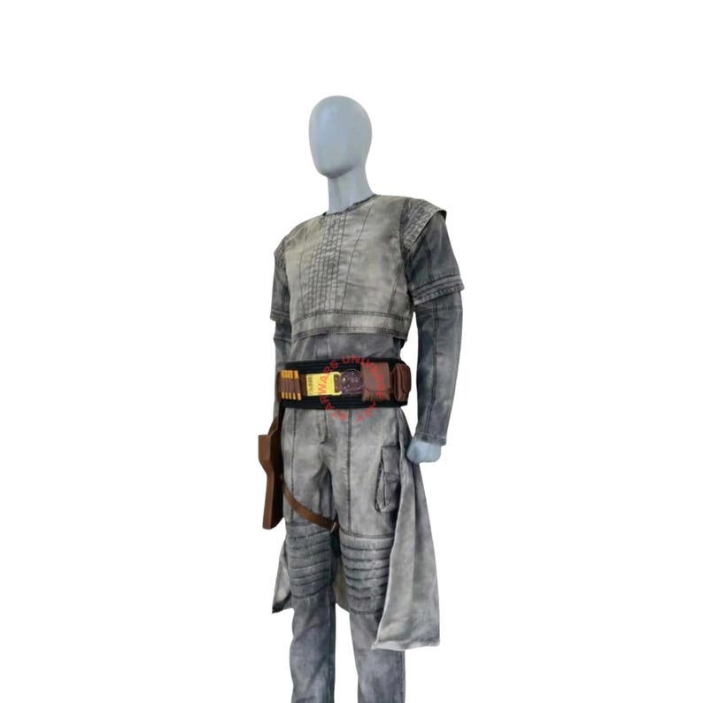 Puede incluir: Un conjunto de disfraz gris texturizado que incluye una parte superior de manga corta con costuras verticales, pantalones a juego con refuerzo en las rodillas y un cintur&oacute;n utilitario negro. El cintur&oacute;n tiene bolsas marrones y cartucheras amarillas.