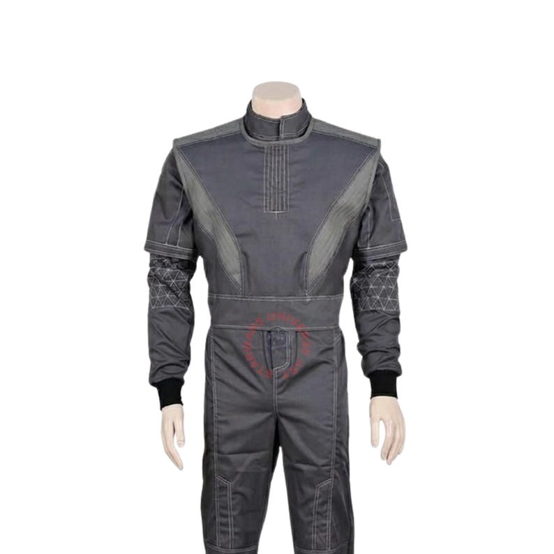 May include: A dark gray jumpsuit featuring a high collar, long sleeves with black cuffs, and a structured bodice with vertical stitching. The sleeves display a geometric triangular pattern, while the pants include reinforced knee panels and visible seams.
