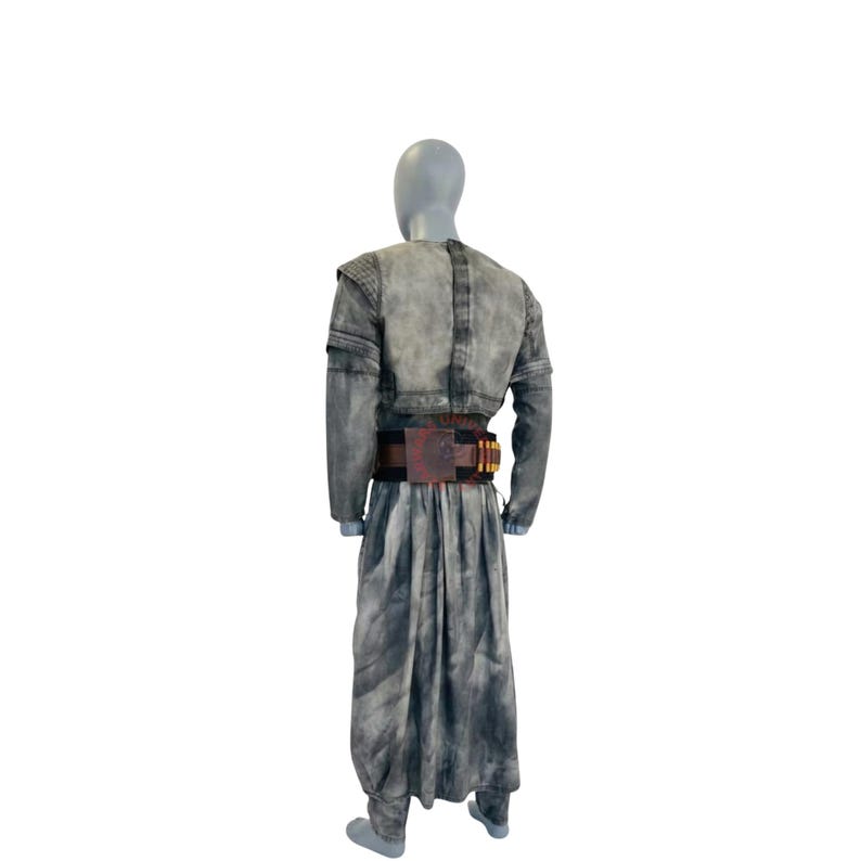 Puede incluir: Un conjunto de t&uacute;nica de manga larga y falda larga a juego con un acabado gris moteado y desgastado. El atuendo incluye un cintur&oacute;n utilitario de color marr&oacute;n oscuro en la cintura, decorado con una hebilla rectangular y trabillas doradas.