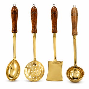 Op de afbeelding: Een set van vier keukengerei met gepolijste goudkleurige metalen koppen en donkerbruine handgrepen met houtnerf. De set bevat een massieve lepel, een ronde schuimspaan, een platte vierkante spatel en een diepe ronde soeplepel met metalen oog.