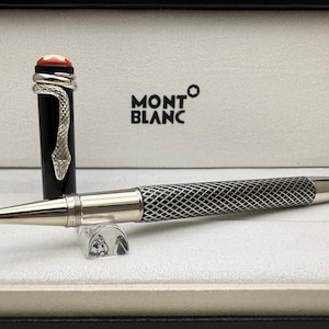 Könnte beinhalten: Ein luxuriöser Montblanc Rollerball-Stift mit schwarzem Schaft und silberfarbenem, rautenförmigem Griff. Die Stiftkappe ist schwarz mit einem silbernen Schlangenmuster und einem roten Stein. Der Stift wird in einer weißen Box mit dem Montblanc-Logo präsentiert.
