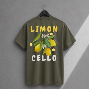 K&ouml;nnte beinhalten: Ein olivgr&uuml;nes T-Shirt mit einem Grafikdruck auf der R&uuml;ckseite. Das Design zeigt gelbe Zitronen, gr&uuml;ne Bl&auml;tter und wei&szlig;e Bl&uuml;ten mit dem gelben Schriftzug LIMON dar&uuml;ber und dem wei&szlig;en Schriftzug CELLO unter der botanischen Abbildung.