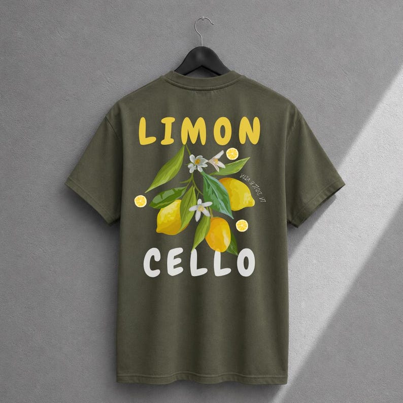 K&ouml;nnte beinhalten: Ein olivgr&uuml;nes T-Shirt mit einem Grafikdruck auf der R&uuml;ckseite. Das Design zeigt gelbe Zitronen, gr&uuml;ne Bl&auml;tter und wei&szlig;e Bl&uuml;ten mit dem gelben Schriftzug LIMON dar&uuml;ber und dem wei&szlig;en Schriftzug CELLO unter der botanischen Abbildung.