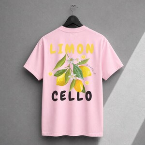 K&ouml;nnte beinhalten: Ein hellrosa T-Shirt mit kurzen &Auml;rmeln und einer Grafik aus gelben Zitronen, gr&uuml;nen Bl&auml;ttern und wei&szlig;en Bl&uuml;ten. Der Text LIMON ist in Gelb &uuml;ber der Grafik gedruckt, und der Text CELLO ist in Schwarz unter der Grafik gedruckt.