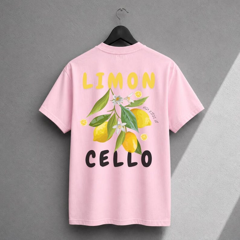 K&ouml;nnte beinhalten: Ein hellrosa T-Shirt mit kurzen &Auml;rmeln und einer Grafik aus gelben Zitronen, gr&uuml;nen Bl&auml;ttern und wei&szlig;en Bl&uuml;ten. Der Text LIMON ist in Gelb &uuml;ber der Grafik gedruckt, und der Text CELLO ist in Schwarz unter der Grafik gedruckt.