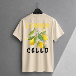 K&ouml;nnte beinhalten: Ein beiges T-Shirt mit kurzen &Auml;rmeln und einer Grafik aus gelben Zitronen, gr&uuml;nen Bl&auml;ttern und wei&szlig;en Bl&uuml;ten. Der Text LIMON ist in Gelb &uuml;ber der Grafik gedruckt, und der Text CELLO ist in Schwarz unter der Grafik gedruckt.