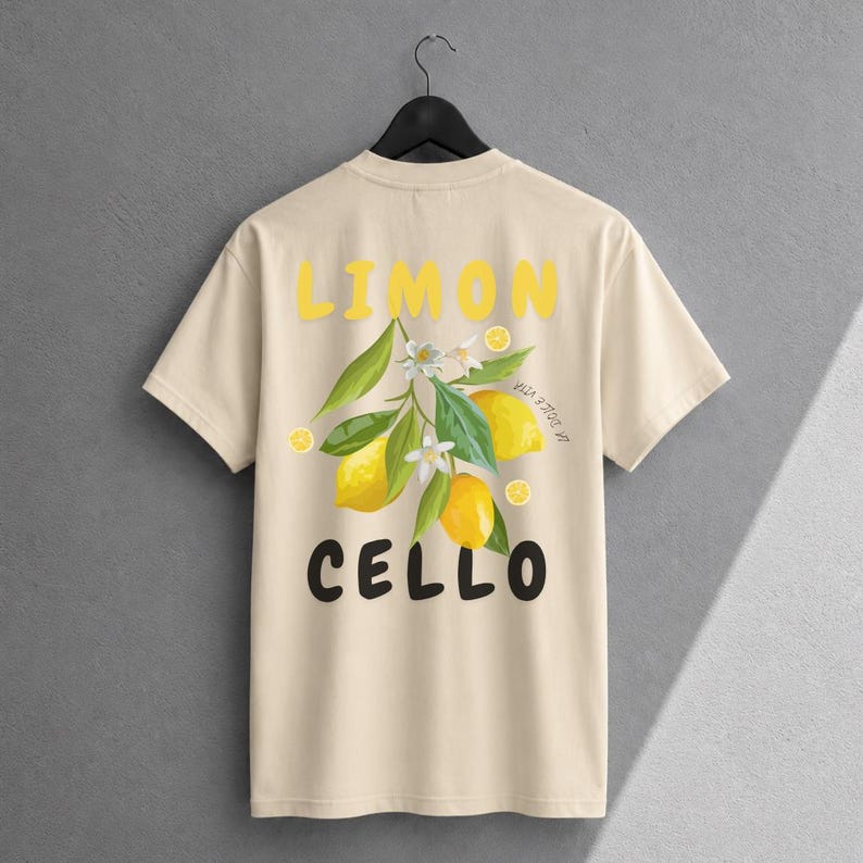 K&ouml;nnte beinhalten: Ein beiges T-Shirt mit kurzen &Auml;rmeln und einer Grafik aus gelben Zitronen, gr&uuml;nen Bl&auml;ttern und wei&szlig;en Bl&uuml;ten. Der Text LIMON ist in Gelb &uuml;ber der Grafik gedruckt, und der Text CELLO ist in Schwarz unter der Grafik gedruckt.