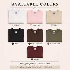 May include: A color chart for a premium heavy cotton unisex t-shirt featuring seven folded shirts in white, light pink, sand, black, dark chocolate, military green, and maroon. The text reads AVAILABLE COLORS, color names, and Choose your favorite color at checkout.