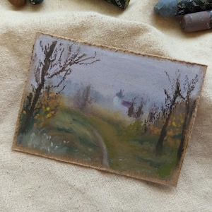 May include: An original landscape painting on a small rectangular canvas. The artwork depicts a path winding through a misty forest, with trees and foliage in muted greens, yellows, and browns. The sky is a soft lavender, and the painting has a rustic, handmade feel.