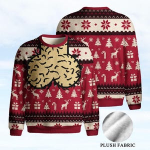Könnte beinhalten: Ein rot-cremefarbener Langarmpullover mit einem wiederkehrenden Weihnachtsmuster aus Rentieren, Tannenbäumen, Zuckerstangen und Geschenken. Die Vorderseite zeigt ein großes, strukturiertes, beiges Grafikdesign. Ein kreisförmiger Einsatz zeigt den Plüschstoff.