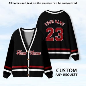 May include: A black V-neck cardigan with white and red stripes on the sleeves and hem, featuring the text Team Name on the front. A matching black sweater displays the text Your Name and the number 23 in red with white outlines on the back.