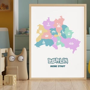 Puede incluir: Una lámina enmarcada con un mapa estilizado de Berlín dividido en secciones de colores pastel. Cada sección contiene un icono blanco que representa monumentos o actividades locales. El texto BERLIN MEINE STADT está en azul oscuro.