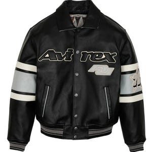 May include: Black leather jacket with white and gray accents on the sleeves. The jacket features the brand name "Avi'rex" in white lettering across the chest, along with a gray and white patch. The jacket has a ribbed collar and cuffs.