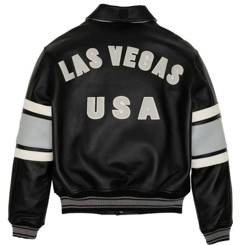 May include: Black leather jacket with the words "LAS VEGAS USA" in white and gray lettering on the back. The jacket has white and gray stripes on the sleeves and a gray and white striped hem and cuffs.