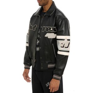 May include: Black leather jacket with white and gray accents. The jacket features the word "M-rex" across the chest and "78" on the sleeve. The jacket has a ribbed collar, cuffs, and hem.