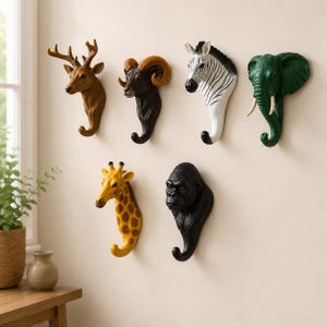 May include: A set of animal head wall hooks, featuring a deer, ram, zebra, elephant, giraffe, and gorilla. Each hook is a different colour and designed to hang items. The hooks are mounted on a neutral wall.