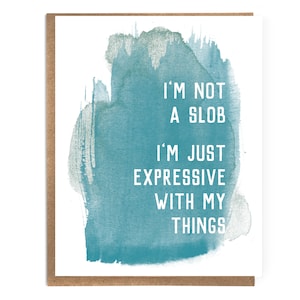 May include: A white card with a teal watercolor background. The card has the text "I'm not a slob I'm just expressive with my things" in white.