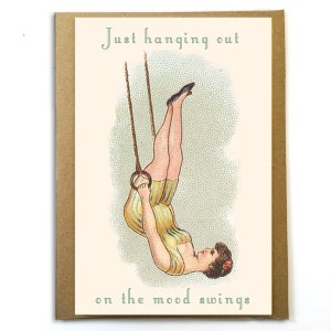 K&ouml;nnte beinhalten: Eine Gru&szlig;karte mit einer Vintage-Illustration einer Frau, die kopf&uuml;ber an einem Trapez h&auml;ngt. Der Text auf der Karte lautet "Just hanging out on the mood swings."
