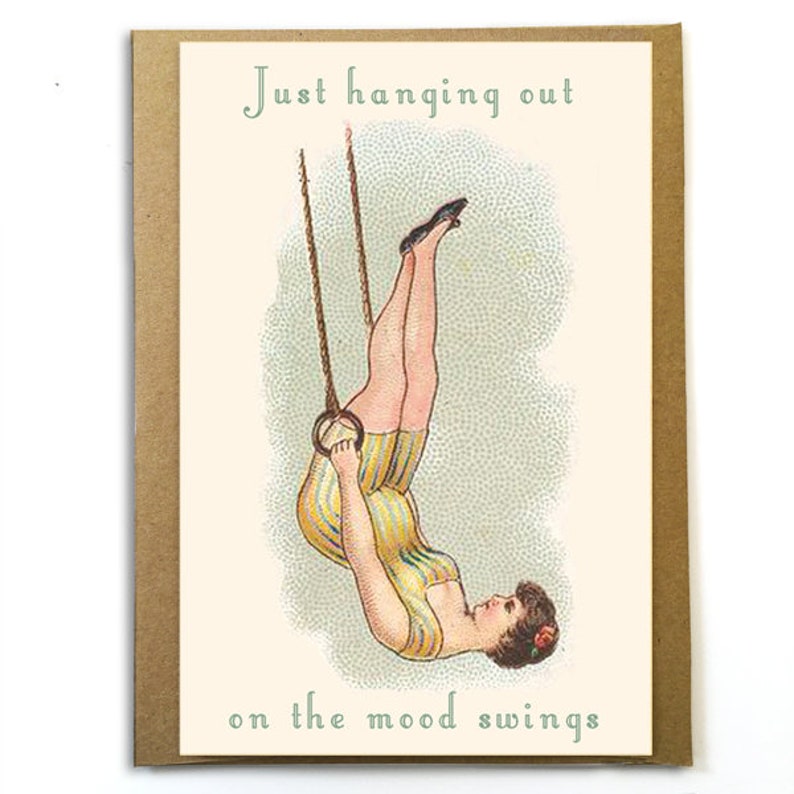 K&ouml;nnte beinhalten: Eine Gru&szlig;karte mit einer Vintage-Illustration einer Frau, die kopf&uuml;ber an einem Trapez h&auml;ngt. Der Text auf der Karte lautet "Just hanging out on the mood swings."