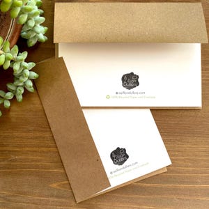 May include: A white card with a black and white logo that says "A Zillion Dollars" and the text "azilliondollars.com" and "100% Recycled Paper and Envelope". The card is on a brown surface.