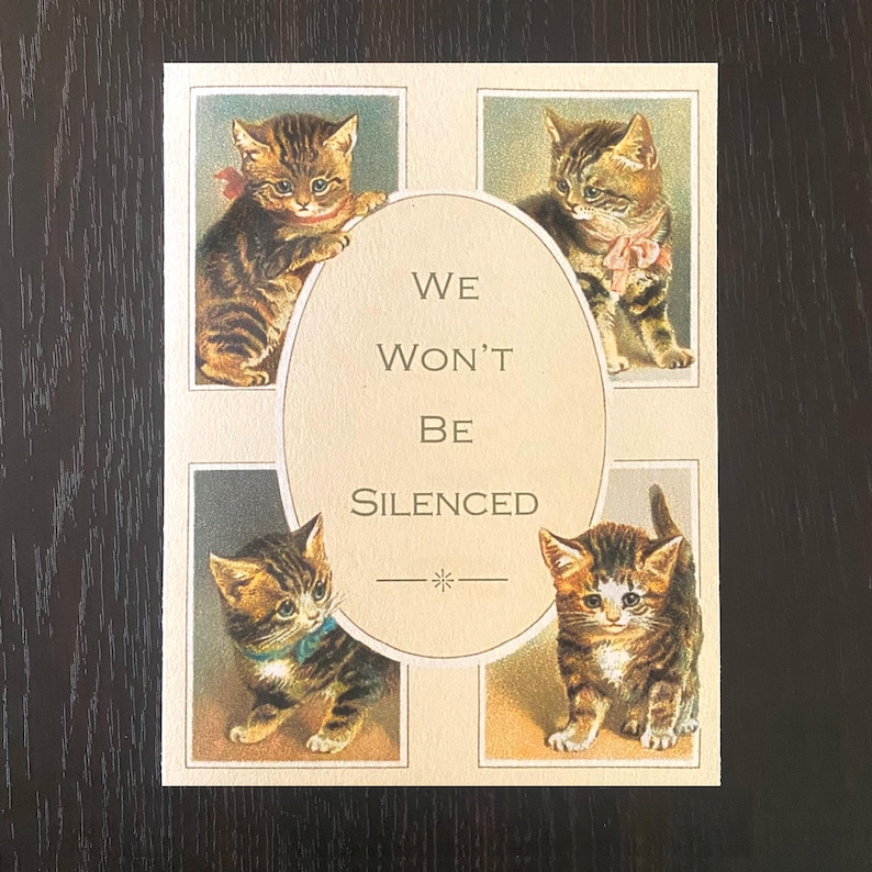 May include: A vintage postcard featuring four kittens in individual frames. The kittens are brown and white with pink and blue ribbons around their necks. The text in the center reads "We Won't Be Silenced".