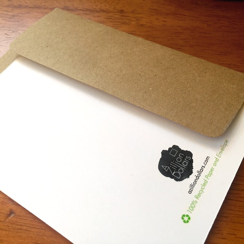 May include: A white card with a black and white logo that says "A zillion dollars" and the text "azilliondollars.com 100% Recycled Paper and Envelope" with a green recycling symbol.