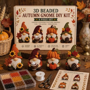 Op de afbeelding: Een 3D-kralen herfstkabouter DIY-set met een doos met tekst, vier afgewerkte kabouterbeeldjes met herfstthema-accessoires, een plastic bakje met gekleurde kralen, wit garen en een instructieblad voor het maken van de figuren.