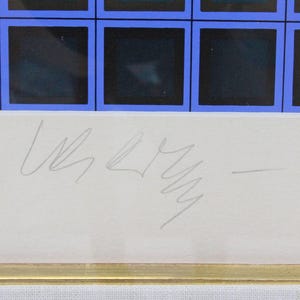 May include: Framed artwork featuring a grid of dark squares with blue borders. The artwork has a white border and a gold frame. A signature is visible in the lower center of the artwork.