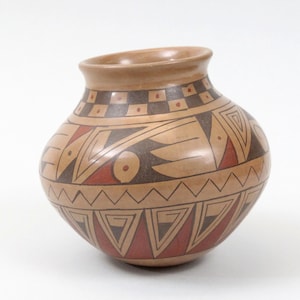 May include: A handcrafted, round pottery vase with a wide opening. The vase features geometric patterns in red, black, and brown against a tan background. The rim is a darker brown color.