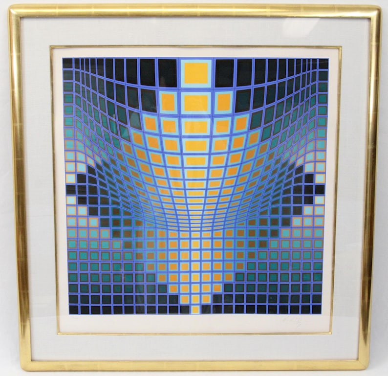 May include: Abstract geometric art print in a gold frame. The artwork features a grid of squares in shades of blue, teal, yellow, and black, creating a three-dimensional effect. The print is mounted on a white mat.