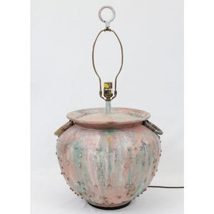 May include: A pink and green ceramic table lamp with a round base and two handles. The base is textured with small bumps and the lampshade is missing.