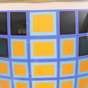 May include: Abstract artwork featuring a grid of squares in a curved pattern. The squares are in shades of black, teal, and orange, outlined in blue and light blue. The artwork is framed in a gold-colored frame.