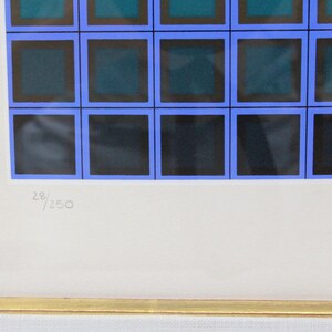 May include: Abstract art print featuring a grid of squares in shades of blue, teal, and black, framed in gold. The print is numbered 28/250. The artwork is mounted on a white background.