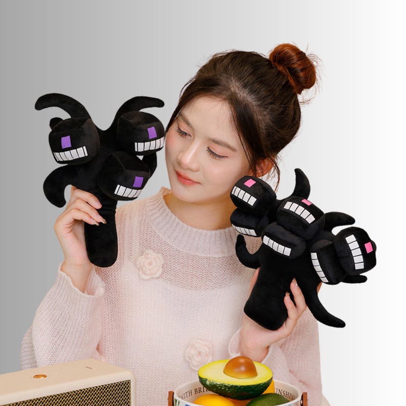 May include: Black plush toy of a three-headed monster with white teeth and purple eyes. The toy has a long handle and is designed to resemble a character from a popular video game. The plush toy is soft and cuddly.