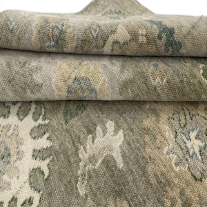 May include: A hand-knotted wool rug featuring a muted color palette of sage green, beige, and soft blue. The surface displays a repeating floral and botanical pattern with intricate, textured pile details and the text Rugs by Ayaan visible.