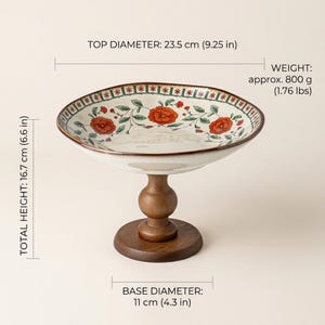 May include: A ceramic pedestal bowl with a floral pattern featuring orange flowers and green leaves. It has a top diameter of 9.25 inches, a base diameter of 4.3 inches, a total height of 6.6 inches, and a weight of approximately 1.76 pounds.